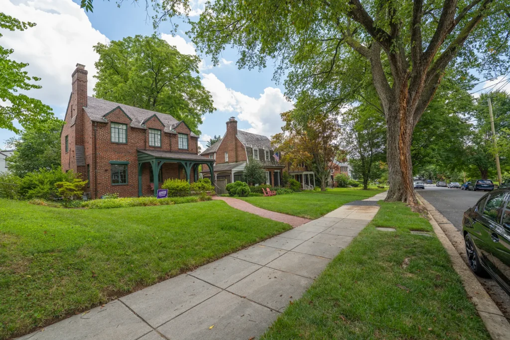 Red-brick Colonial homes with a green front porch and wide lawns on a tree-lined street in American University Park, Washington, DC