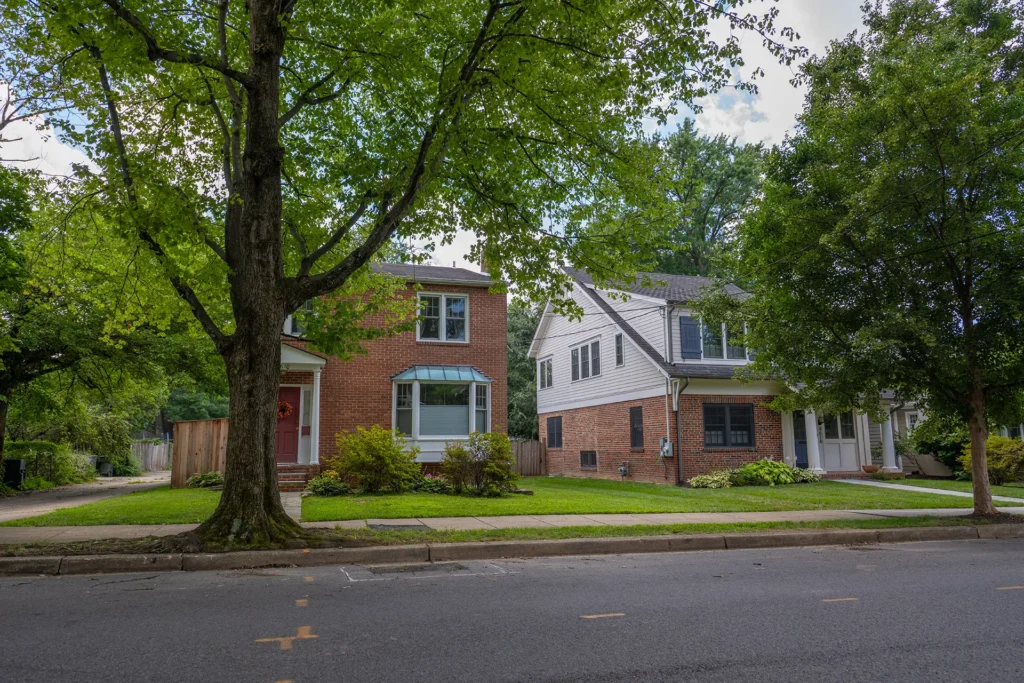 Brick and white-sided Colonial homes beneath mature shade trees in American University Park, Washington, DC