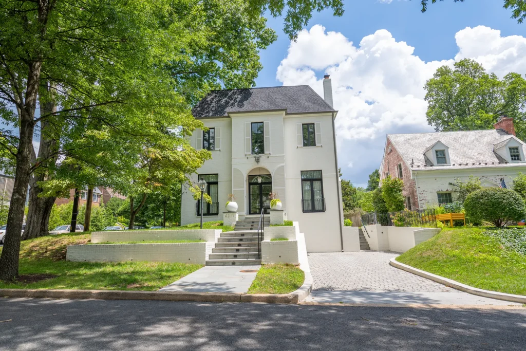 Newly built white stucco home with arched entry and paver driveway in American University Park, Washington, DC